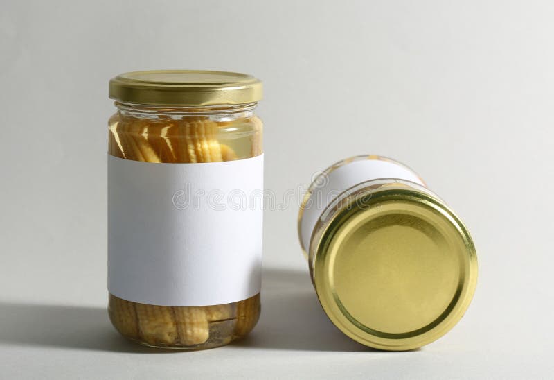 Glass Jars with Pickled Baby Corn on White Background Stock Photo