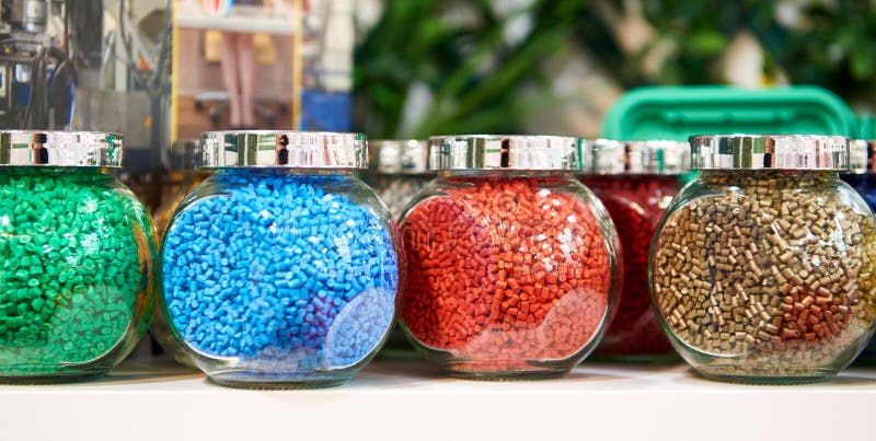 Glass jars with samples of plastic colored granules royalty free stock photos