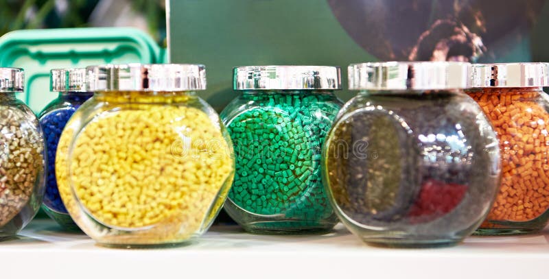 Glass jars with samples of plastic colored granules stock photos