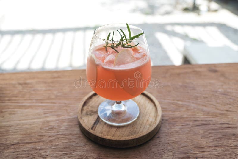 A glass of litchi fruit juice on wooden saucer and table in cafe