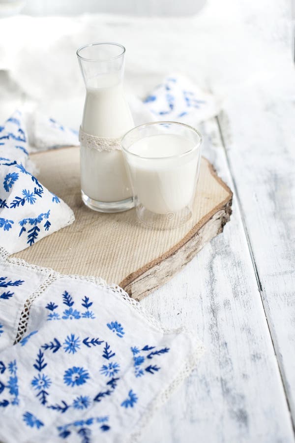 A glass of milk and a bottle of milk. A cotton branch and a towel embroidered with blue flowers. White background and free space