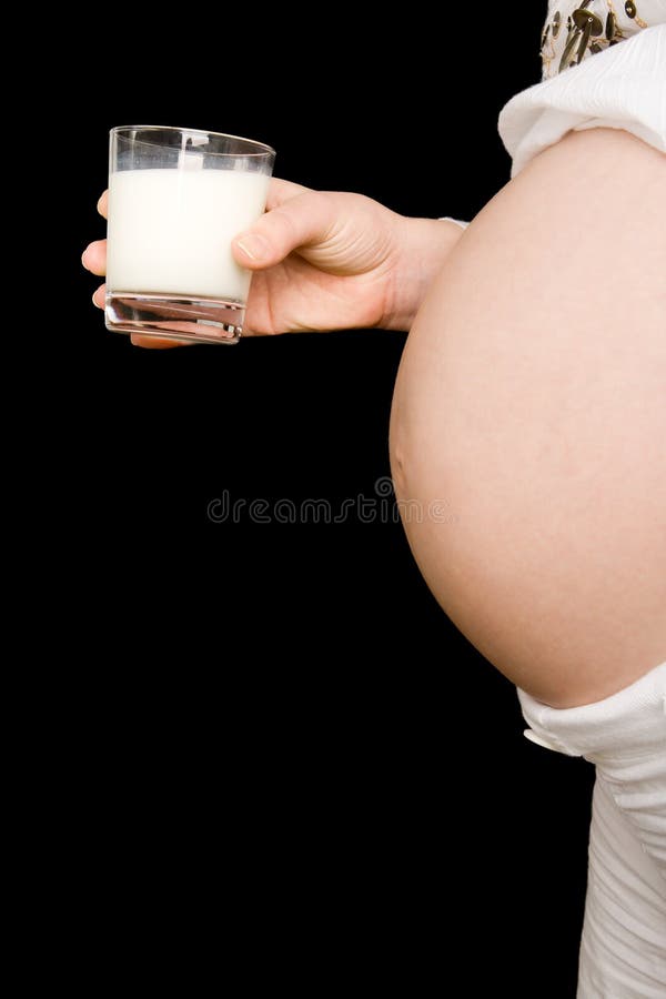 A glass of milk and a pregnant tummy royalty free stock image