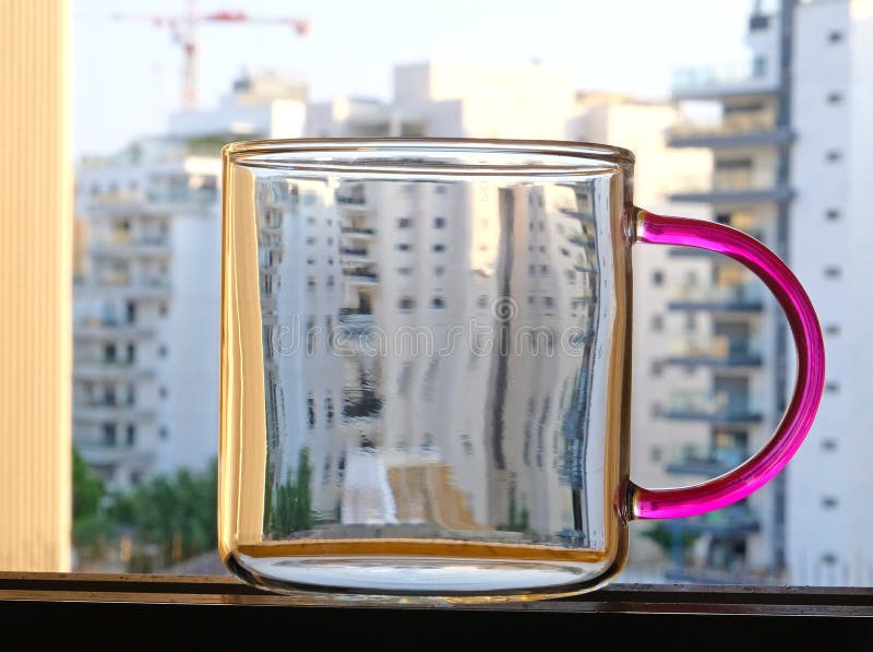 A Glass Mug with a Colored Handle, Standing in the Window Aperture