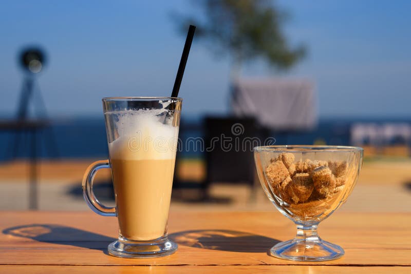Glass mug with latte and salt shaker and sugar bowl with cane sugar on wooden table royalty free stock photography Glass mug with latte and salt shaker and sugar bowl with cane sugar on wooden table royalty free stock photography