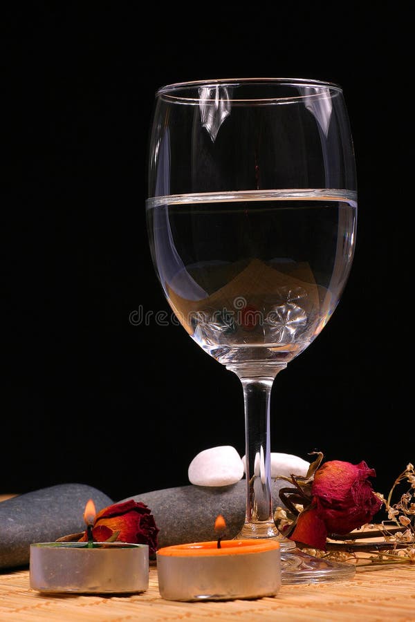 Glass, natural bebbles and dried flowers on the rattan background