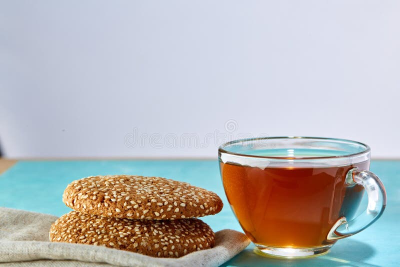 Glass närbild för kopp te- och havremjölchokladkakor på blå bakgrund royaltyfria bilder Glass närbild för kopp te- och havremjölchokladkakor på blå bakgrund royaltyfria bilder