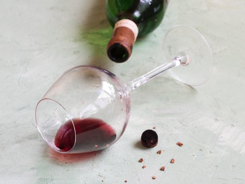 A glass of old wine, a bottle and a broken cork are laid out on the table