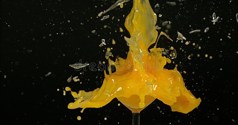 Glass of Orange Exploding against Black Background royalty free stock image