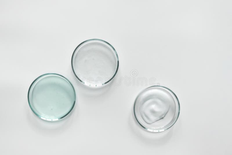 Glass petri dish with different cosmetic products on white background. Shampoo, hair conditioner or mask and shower gel