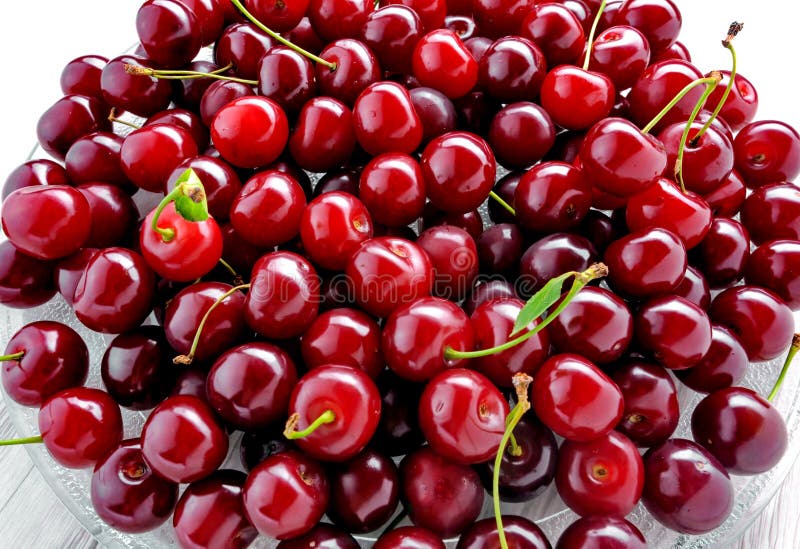 Glass plate of fresh cherry berries close-up on white background royalty free stock images Glass plate of fresh cherry berries close-up on white background royalty free stock images