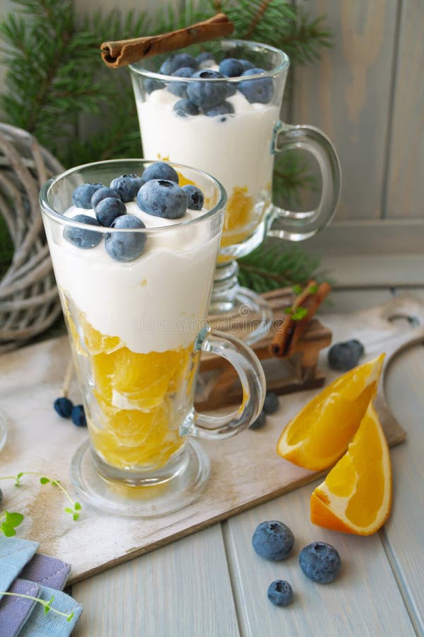 Glass pubs with mousse dessert in orange, blueberry and cream yogurt, vertical image