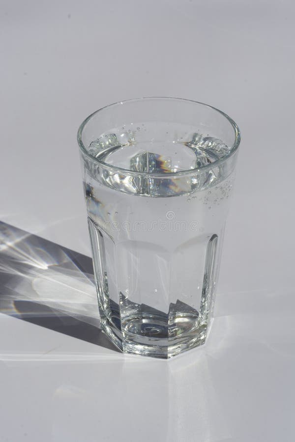 A glass of pure water under sunlight with deep stylish shadows copy space