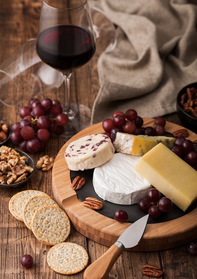 Glass of red wine with selection of various cheese on the board and grapes on wooden background. Blue Stilton, Red Leicester and royalty free stock image Glass of red wine with selection of various cheese on the board and grapes on wooden background. Blue Stilton, Red Leicester and royalty free stock image