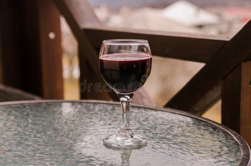 A glass of red wine on table.