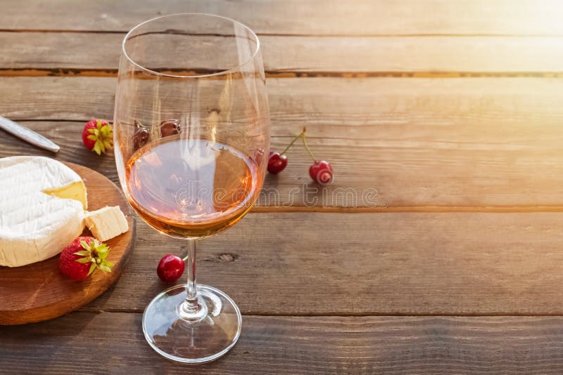 A glass of rose wine standing on rustic wooden table