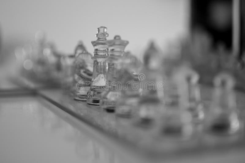 Glass set of chess pieces blurred with the queen and the king focused royalty free stock photo