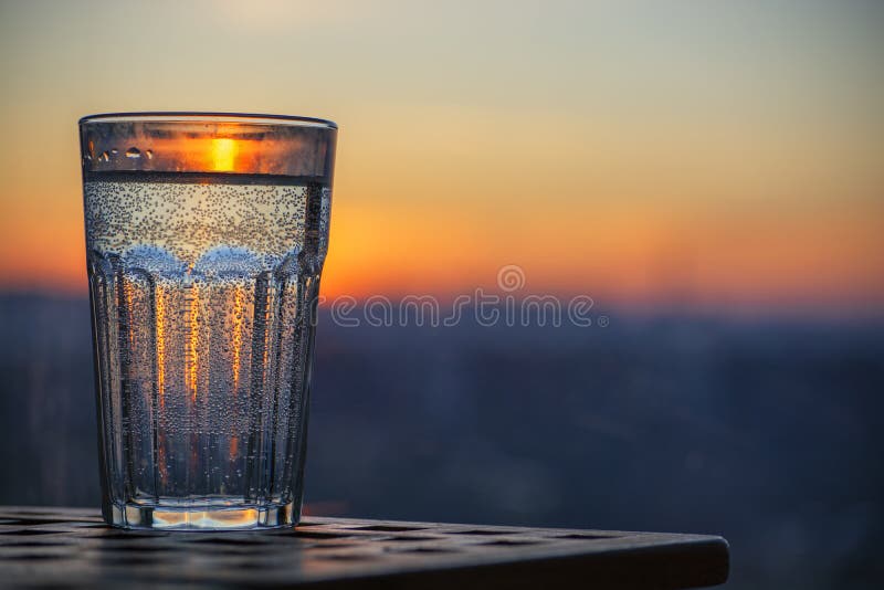 Glass of sparkling water at sunset. Summer evening