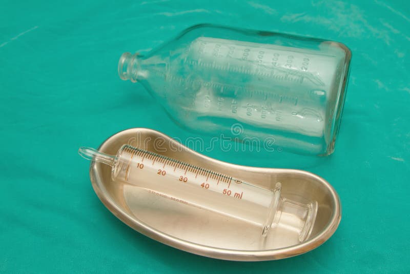 Glass syringe in sterile basin and glass bottle