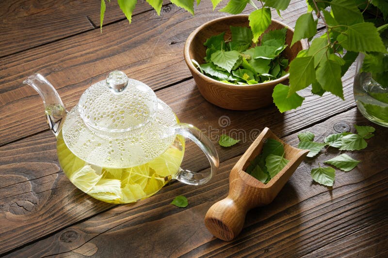 Glass teapot with birch leaf tea. Tea Herbal tea kettle and bowl of leaves of Birch tree. Alternative medicine stock image