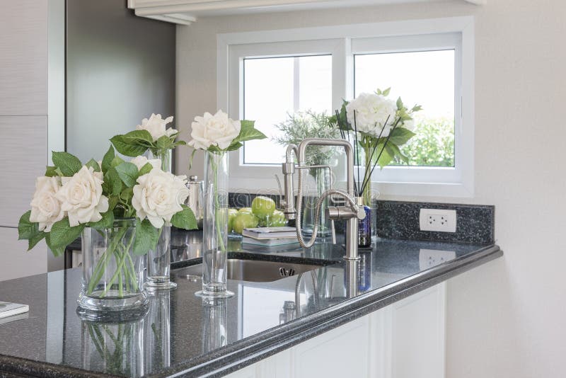 Glass vase of flower on black granite counter in classic pantry room