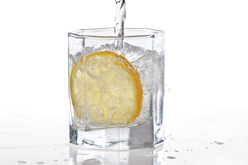 Glass of water, ice and slice of lemon with splash