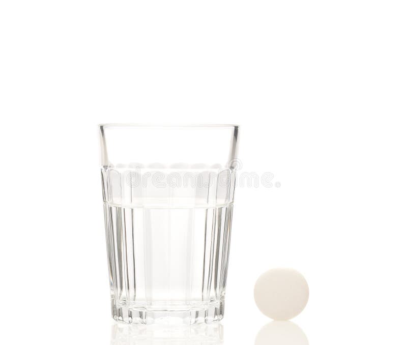 A glass of water and a single aspirin tablet on white royalty free stock photography A glass of water and a single aspirin tablet on white royalty free stock photography