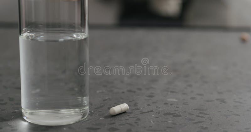 Glass Of Water And White Pill On Terrazzo Countertop Stock Image