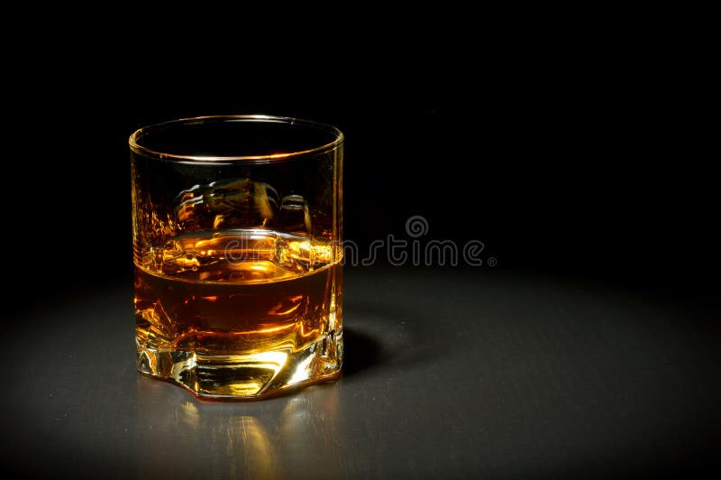 Glass of whiskey on black table
