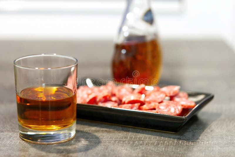 Glass of Whiskey with Buttle and Snack on Black Plate. Stock Image