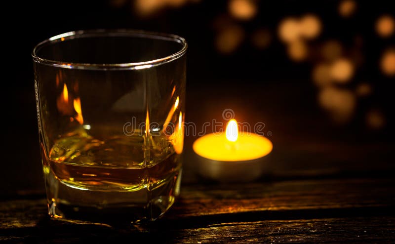 Glass of whiskey on dark wooden table with candlelight and bokeh. Bokeh whiskey stock images, royalty-free photos and pictures