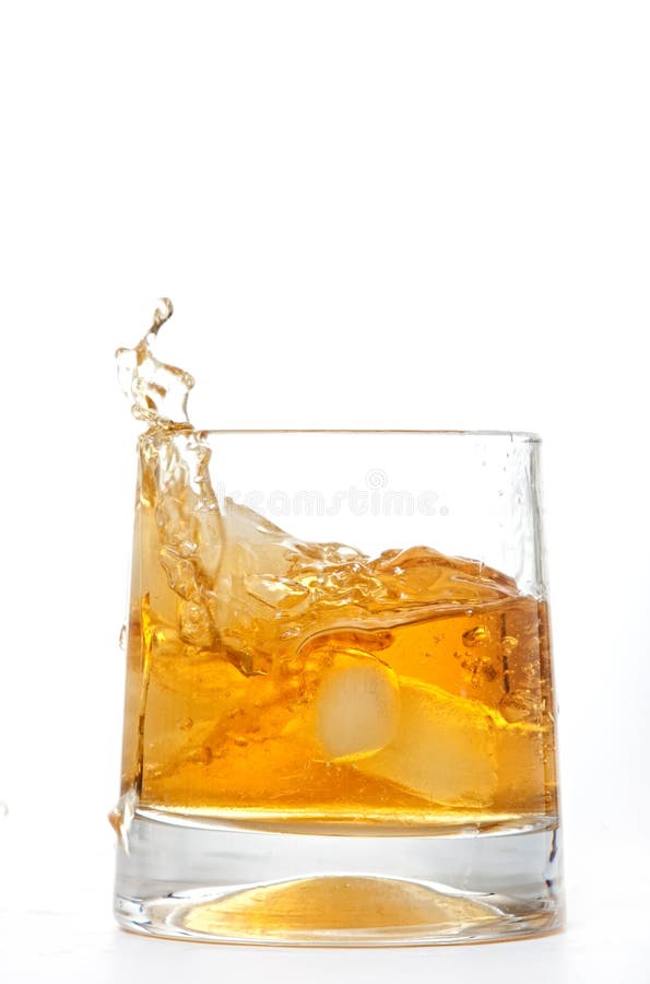 Glass of whiskey with ice cubes splashing