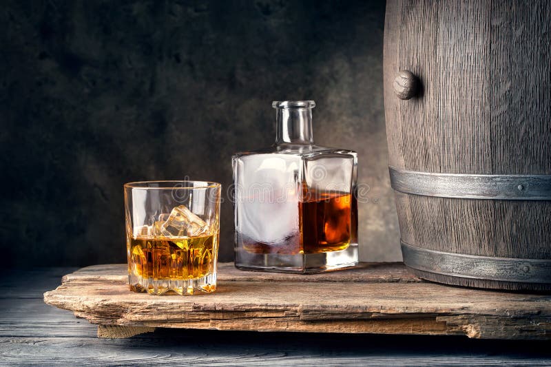 Glass of whiskey with ice decanter and barrel