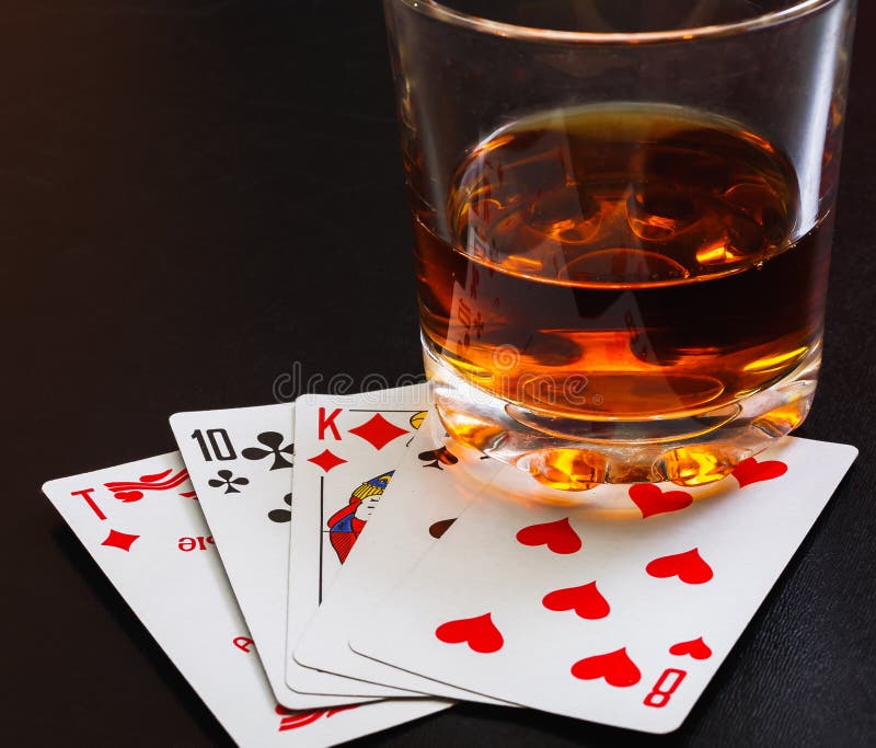 Glass Of Whiskey And Playing Cards On A Black Desk On The Wooden Table