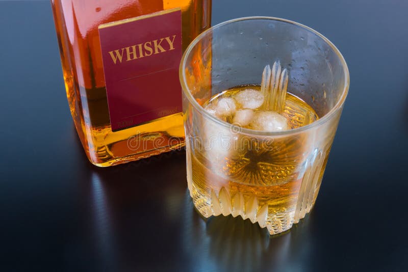 Glass of Whisky with Ice Against the Whisky Bottle Stock Image Image