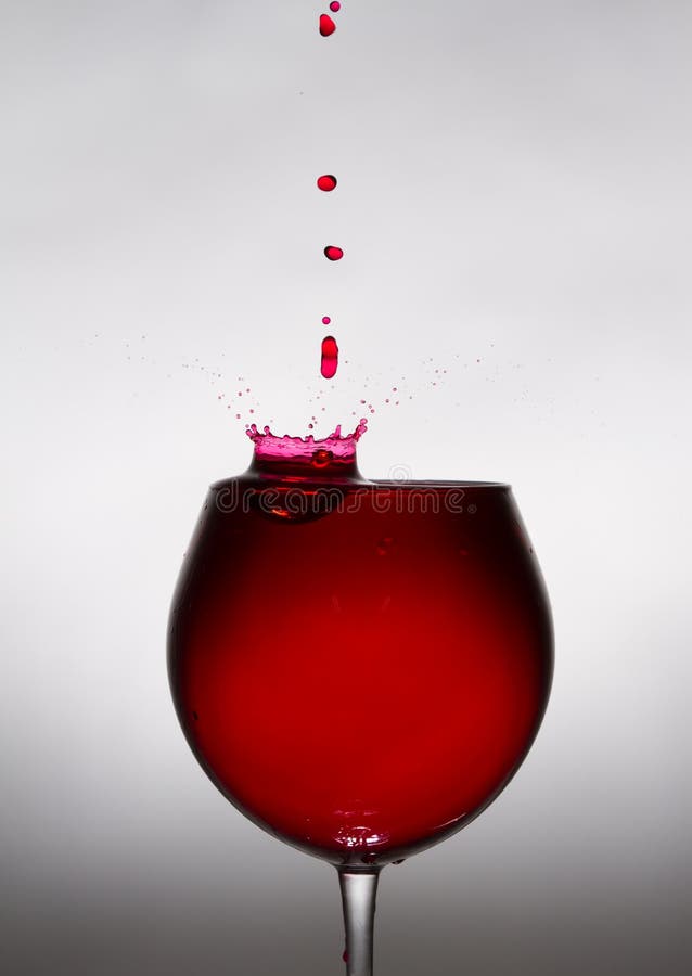 A glass of wine and a drop falling into it