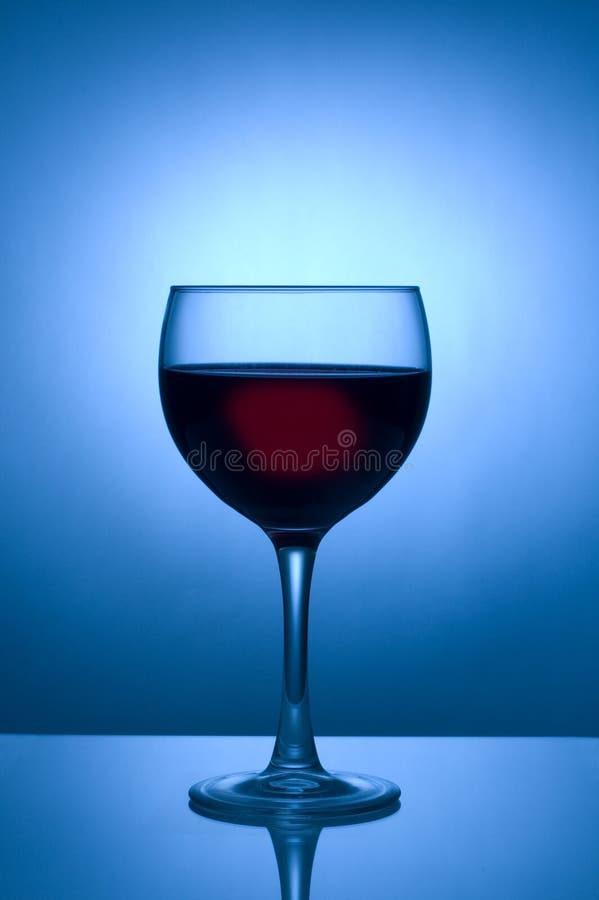 Glass of wine silhouetted against blue spotlight