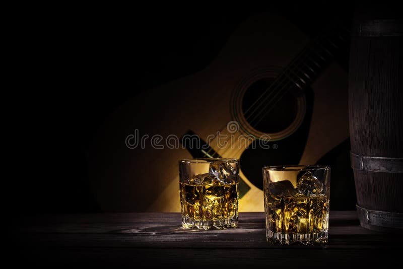 Glasses and barrel of whiskey on background of guitar