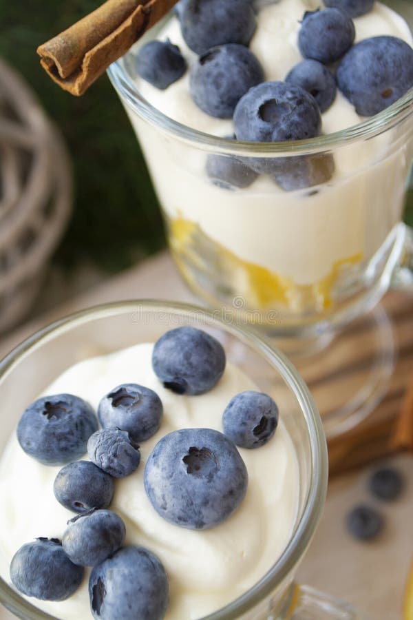 Glasses with blueberry and orange parfait with whipped sour cream. Christmas table, vertical image