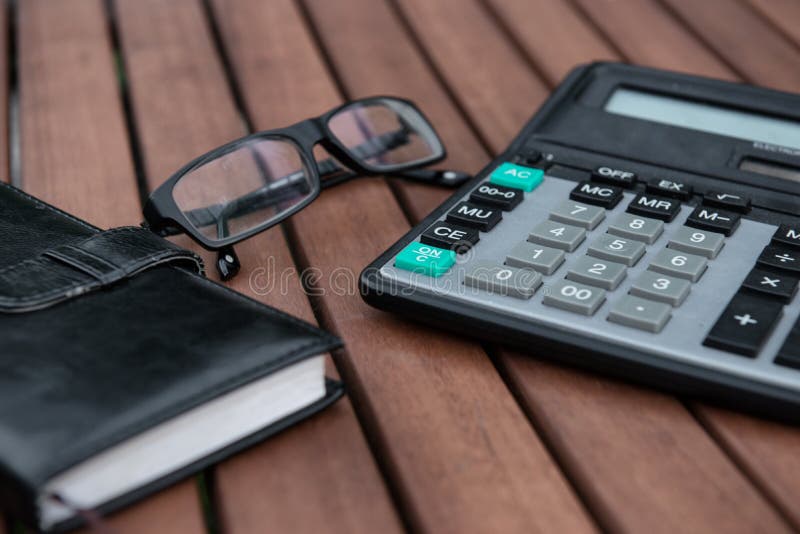 Glasses, calculator, notepad on wooden table royalty free stock image
