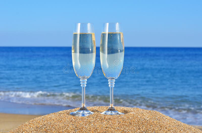Glasses of champagne on the beach sand