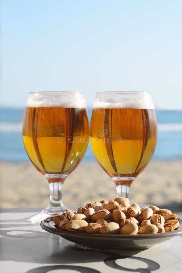 Glasses of Cold Beer and Pistachios on Table Near Sea Stock Image