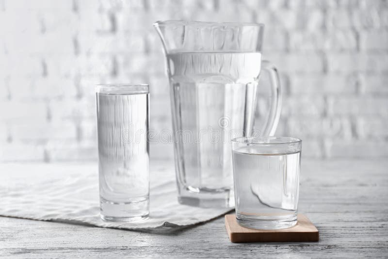 Glasses of fresh water and jug on light table royalty free stock photos Glasses of fresh water and jug on light table royalty free stock photos