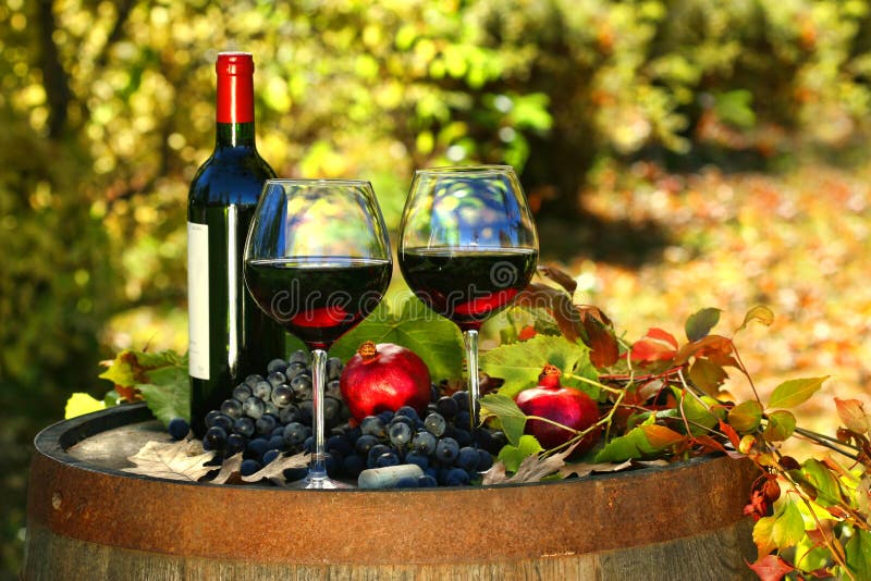 Bicchieri di vino rosso su un vecchio barile con foglie di autunno.