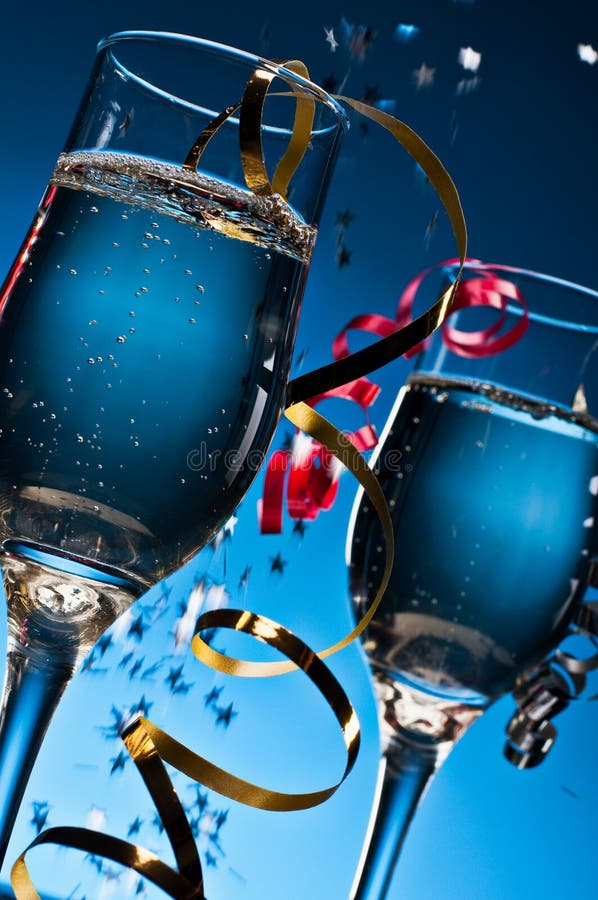 Two glasses of sparkling wine on a blue background with festive streamers.