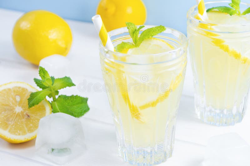 Glasses with summer drink lemonade, lemon fruit and mint leaves on white wooden table stock photo Glasses with summer drink lemonade, lemon fruit and mint leaves on white wooden table stock photo