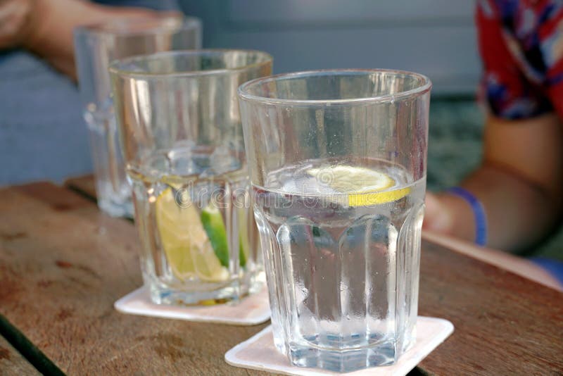 Glasses with water, lemon and lime slices on a table in an outdoor restaurant.