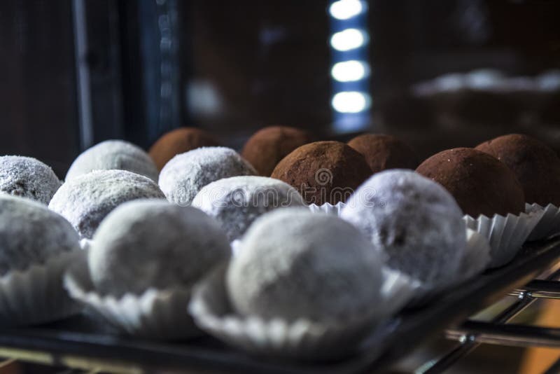Glasshowfenster mit Beleuchtung in der Kaffeestube mit den Ballsüßigkeiten weiß und Schokolade Geschmackvolle Bonbons Kuchen stockbild Glasshowfenster mit Beleuchtung in der Kaffeestube mit den Ballsüßigkeiten weiß und Schokolade Geschmackvolle Bonbons Kuchen stockbild