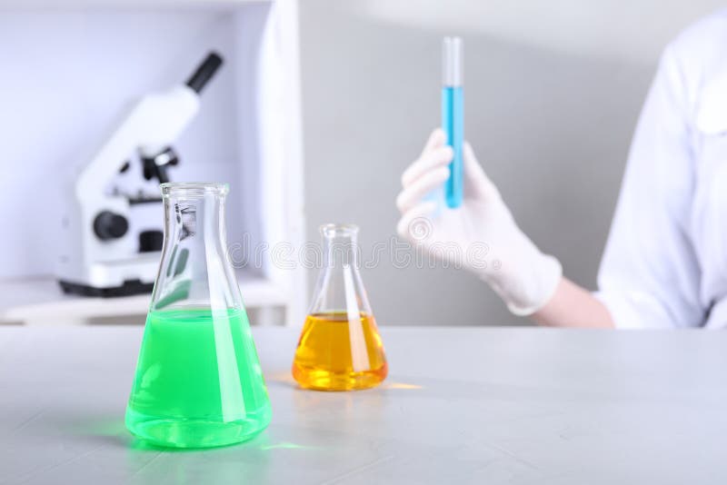 Glassware with samples on table and assistant in laboratory royalty free stock photography Glassware with samples on table and assistant in laboratory royalty free stock photography