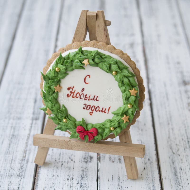 A glaze Christmas gingerbread cookie in the form of a Christmas wreath with a red bow and golden stars with inscription in Russian royalty free stock photo A glaze Christmas gingerbread cookie in the form of a Christmas wreath with a red bow and golden stars with inscription in Russian royalty free stock photo