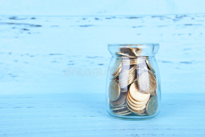 Glazen spaarpot tegen blauwe achtergrond stock foto
